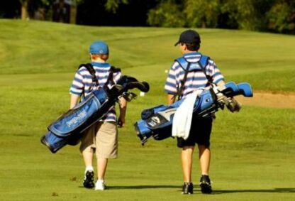 two junior golfers walking on golf course fairway